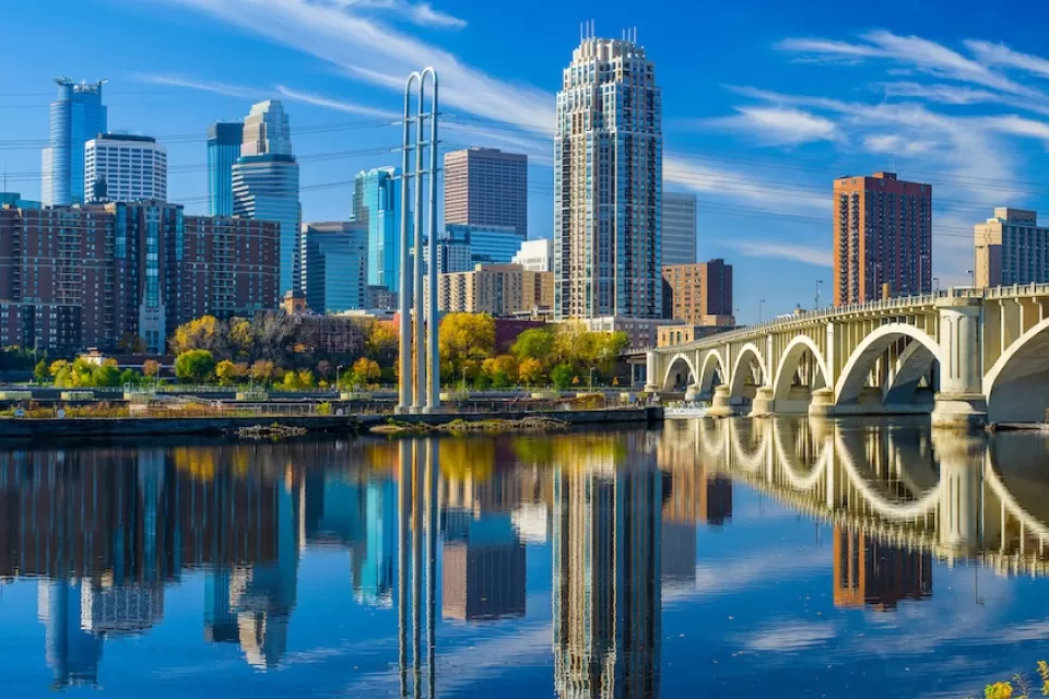 Minneapolis, Minnesota skyline with river and bridge in foreground.